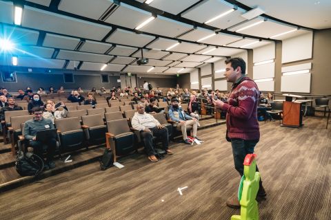 Founder on stage at Stanford holding the green kid figure